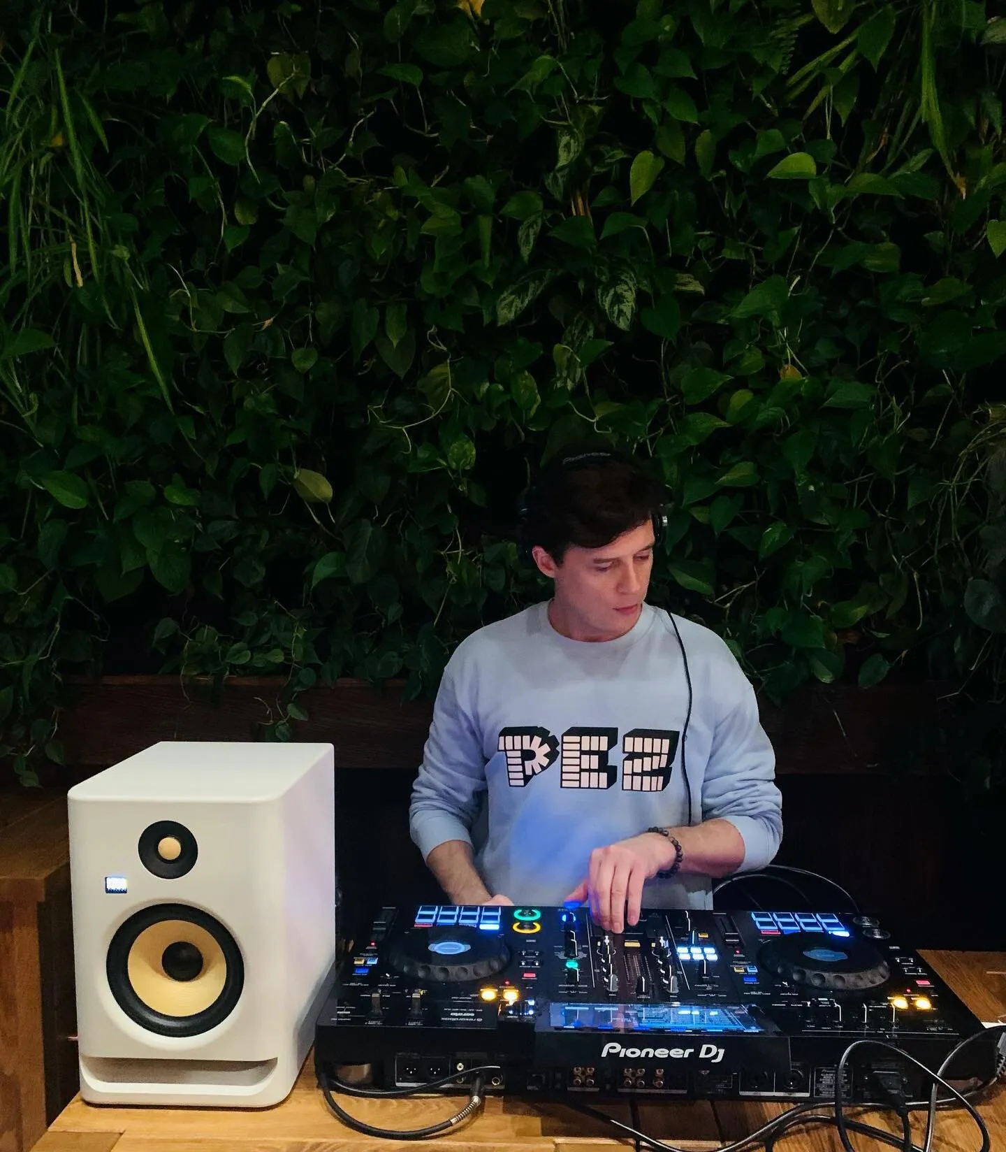 Luke Erb behind the decks against a living green wall at The Farm, Warsaw